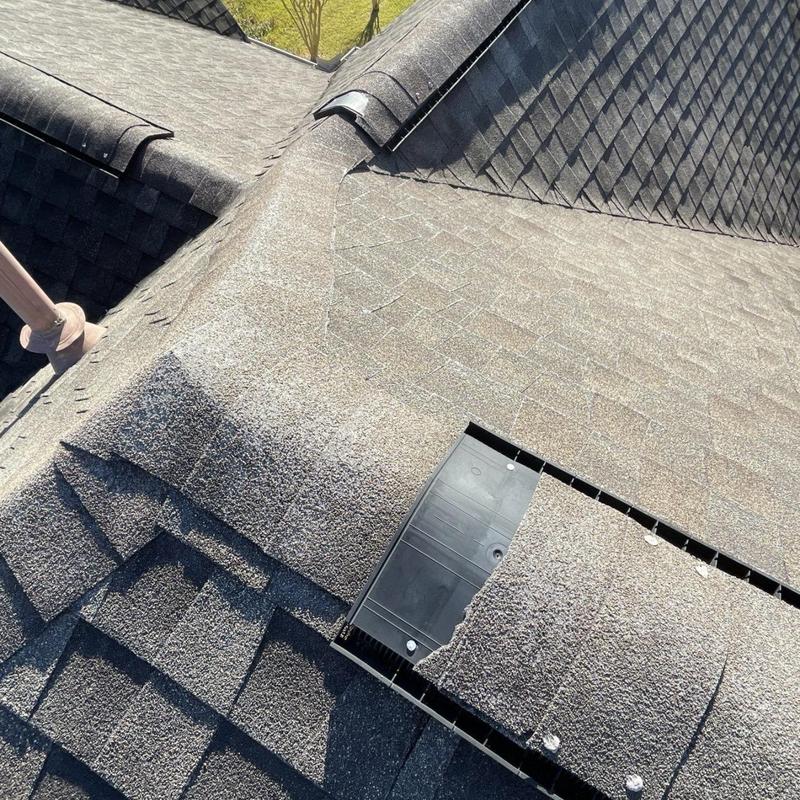 Roof ridge vent with damaged shingles and exposed fasteners