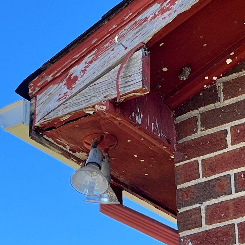 Wood fascia with peeling paint and exterior light fixture