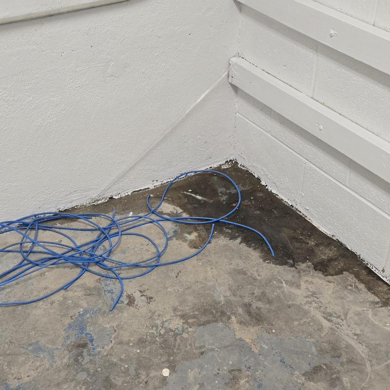 Concrete floor water damage and cables in corner