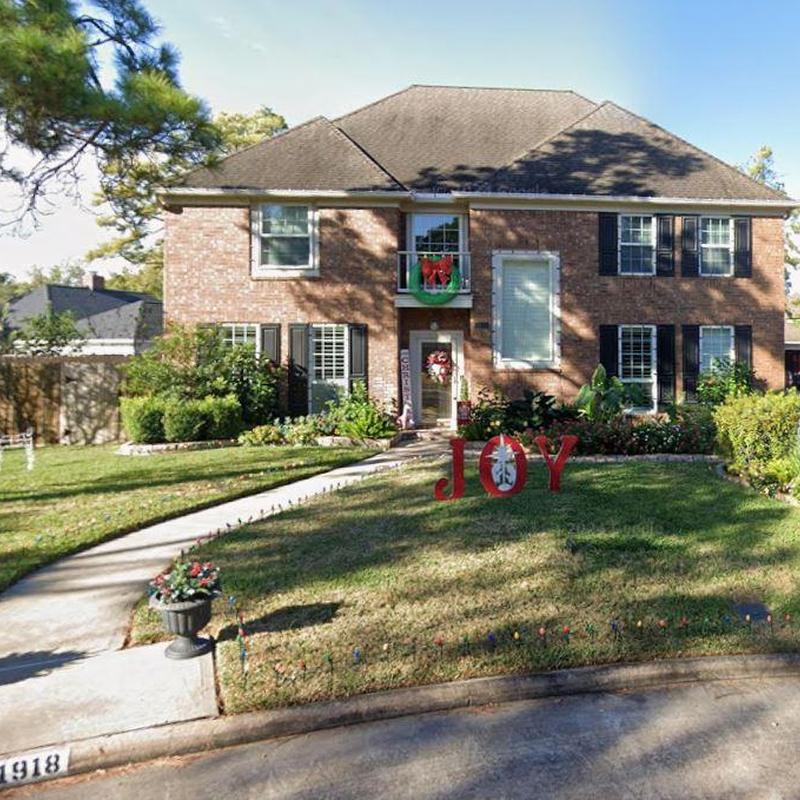 Brick house exterior with holiday decorations and lawn sign