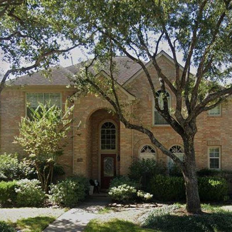 Residential brick roof with trees and landscaping in front