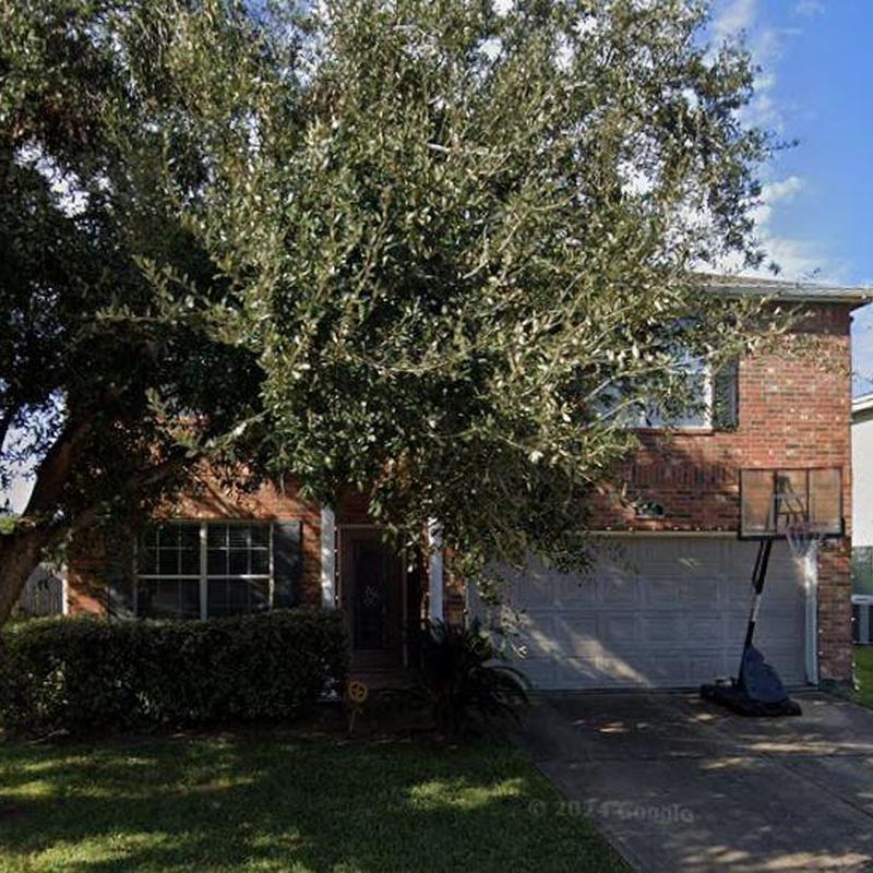 Two-story brick house with large tree in front yard