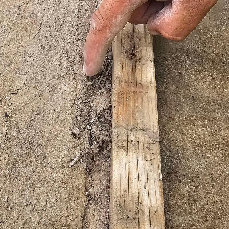 Concrete driveway crack with wood board and finger pointing Concrete driveway crack with wood board and finger pointing