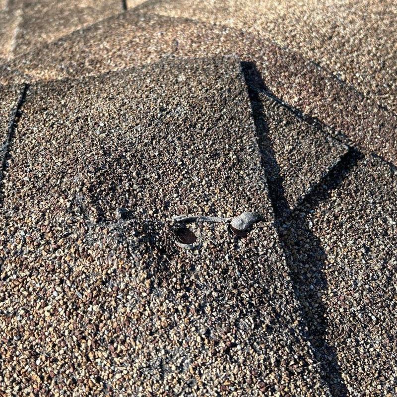 Asphalt shingles with popped nail during roof inspection