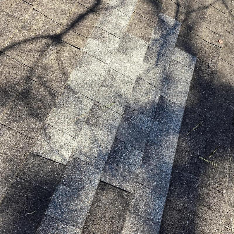 Roof shingles with replaced damaged sections under sunlight