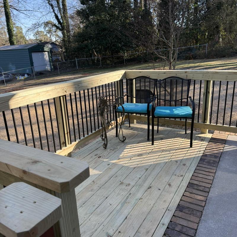 Attached wooden deck with metal railing and seating