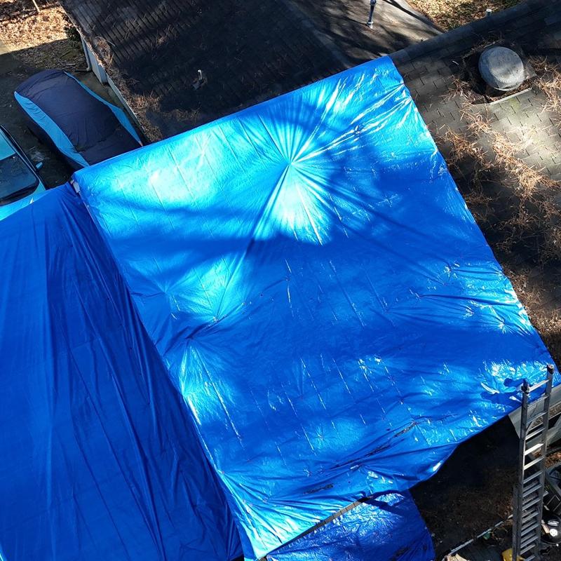 Roof decking covered with blue tarp during replacement