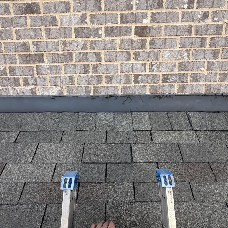 Roof flashing on brick wall with asphalt shingles