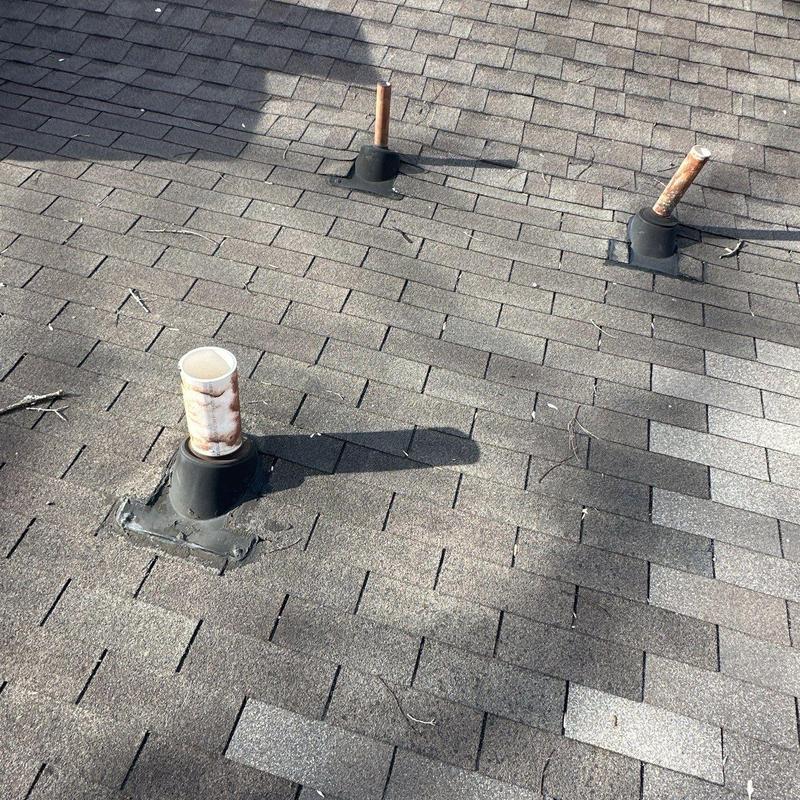 Roof vent pipes on shingled rooftop with hail damage