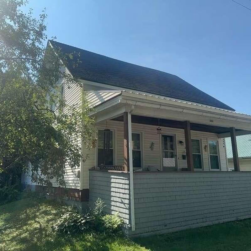 Residential asphalt shingle roof with front porch in sunlight