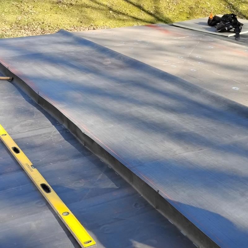 EPDM rubber roofing installation with level tool