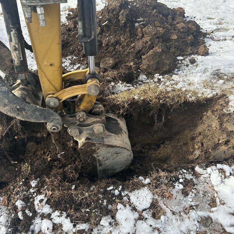 Sewer line excavation with mini excavator in snowy ground