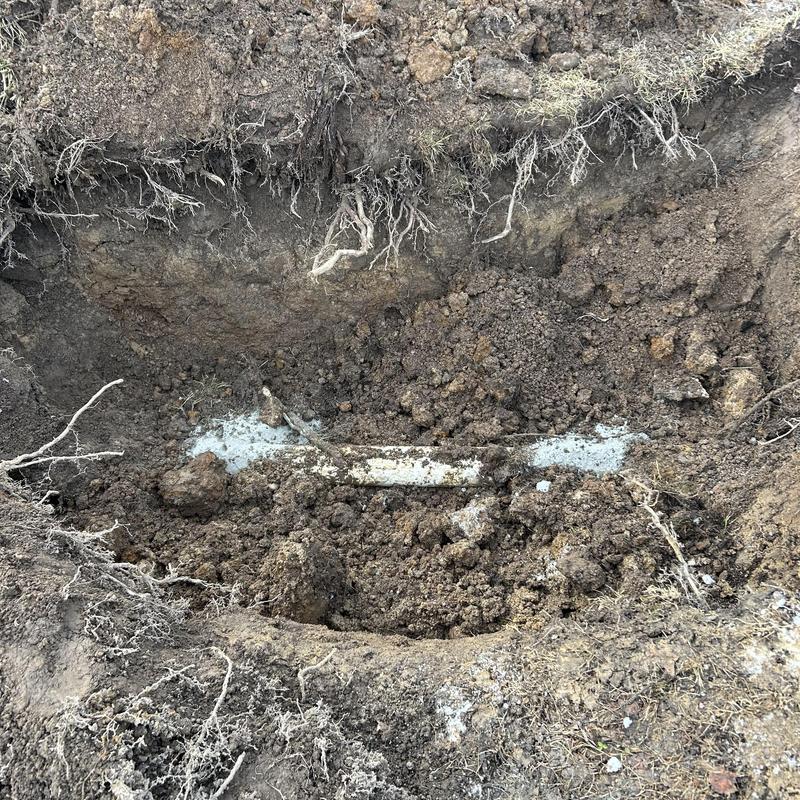 Sewer line excavation exposing buried pipe section
