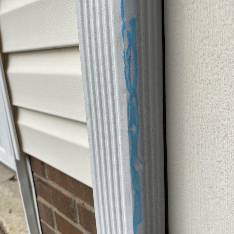 Downspout with blue sealant marks on exterior wall