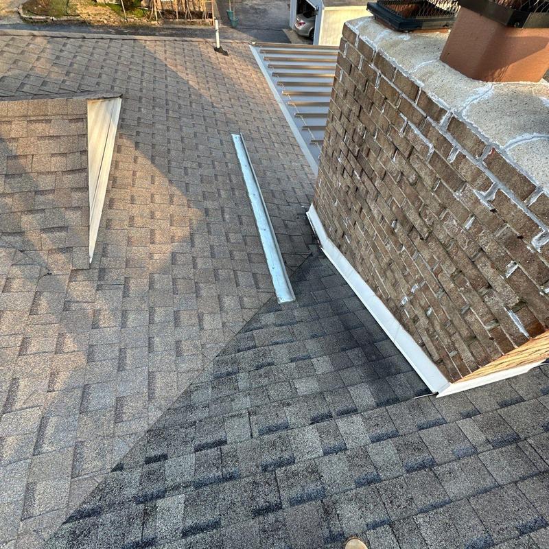 Roof flashing and chimney base inspection on shingle roof