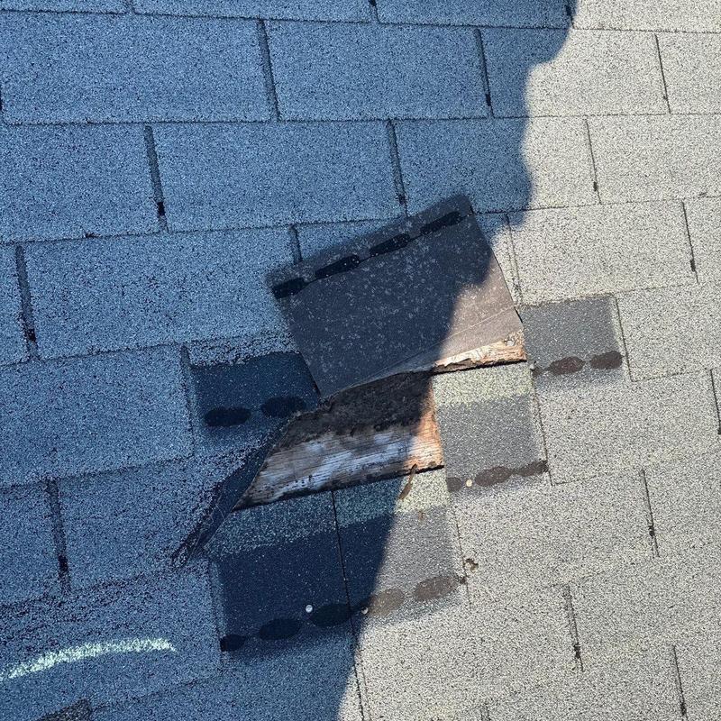Roof shingles with visible hail damage and wood exposure