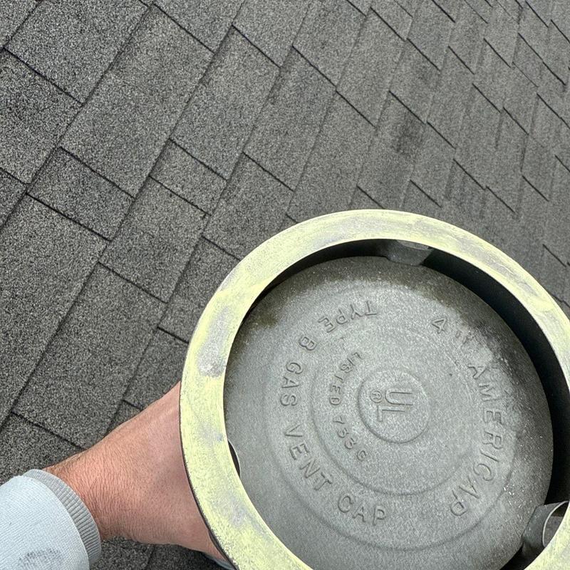 Gas vent cap on shingle roof showing hail damage