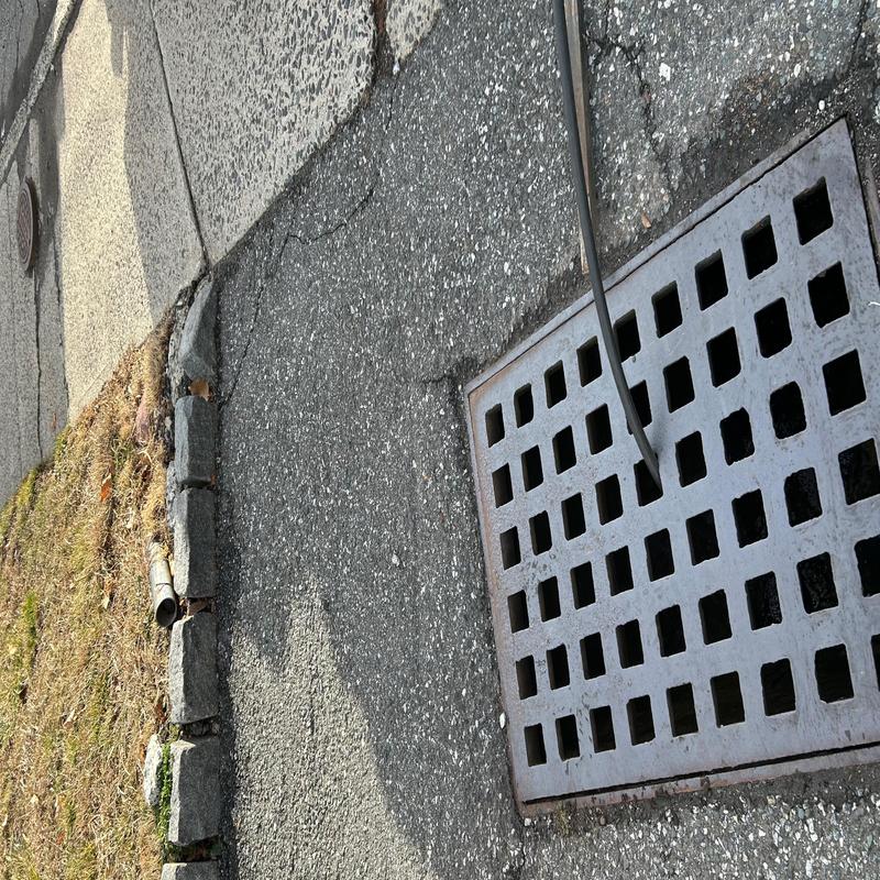 Storm drain with cleaning hose on asphalt road
