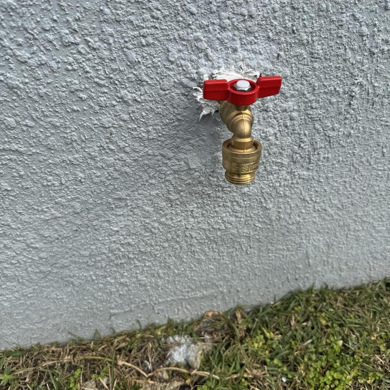 12-inch hose bib with red handle on stucco wall