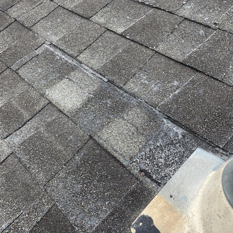 Asphalt shingles with damaged and repaired sections on roof