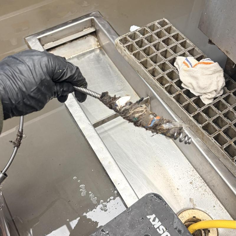 Trench drain clogged debris removal with sewer snake