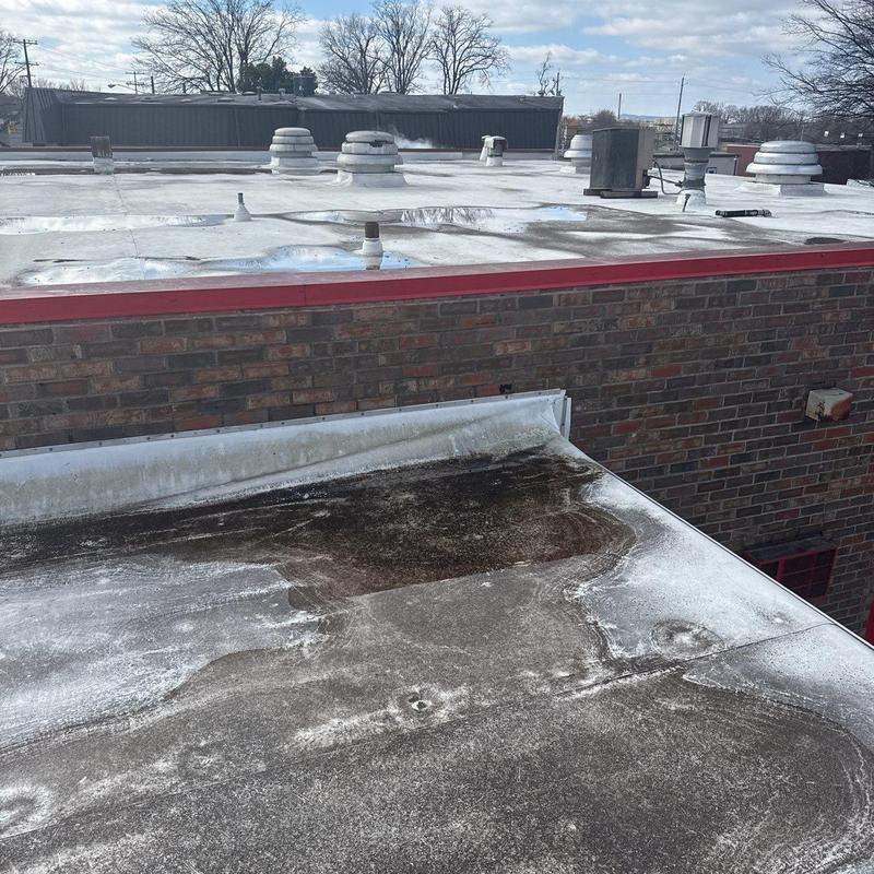 Flat roof surface with water pooling and damage signs