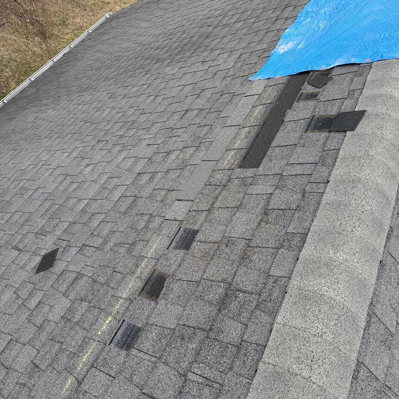 Asphalt shingle roof with hail damage and blue tarp