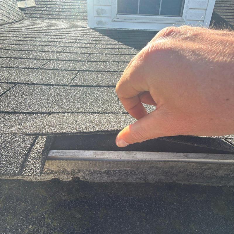 Roof shingles with lifted edge near flashing inspection