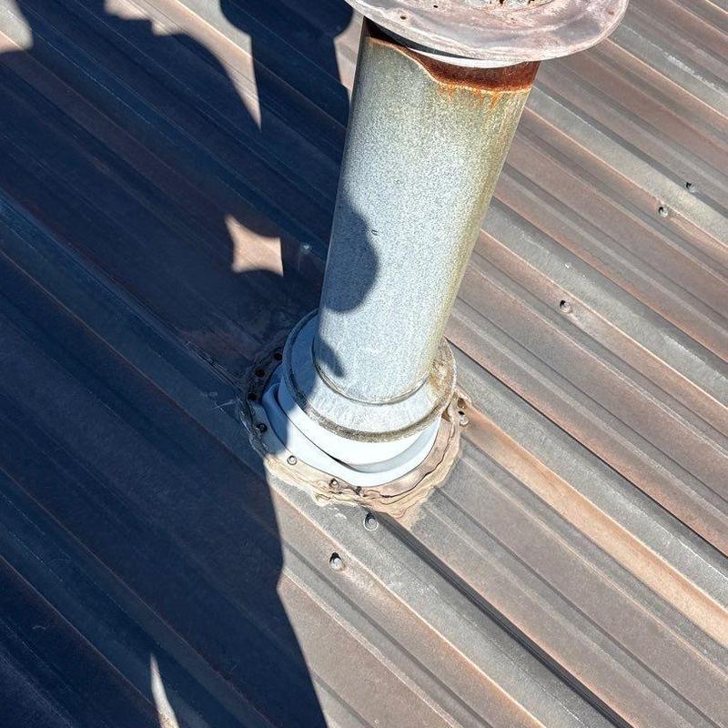 Metal pipe flashing on rusted commercial metal roof