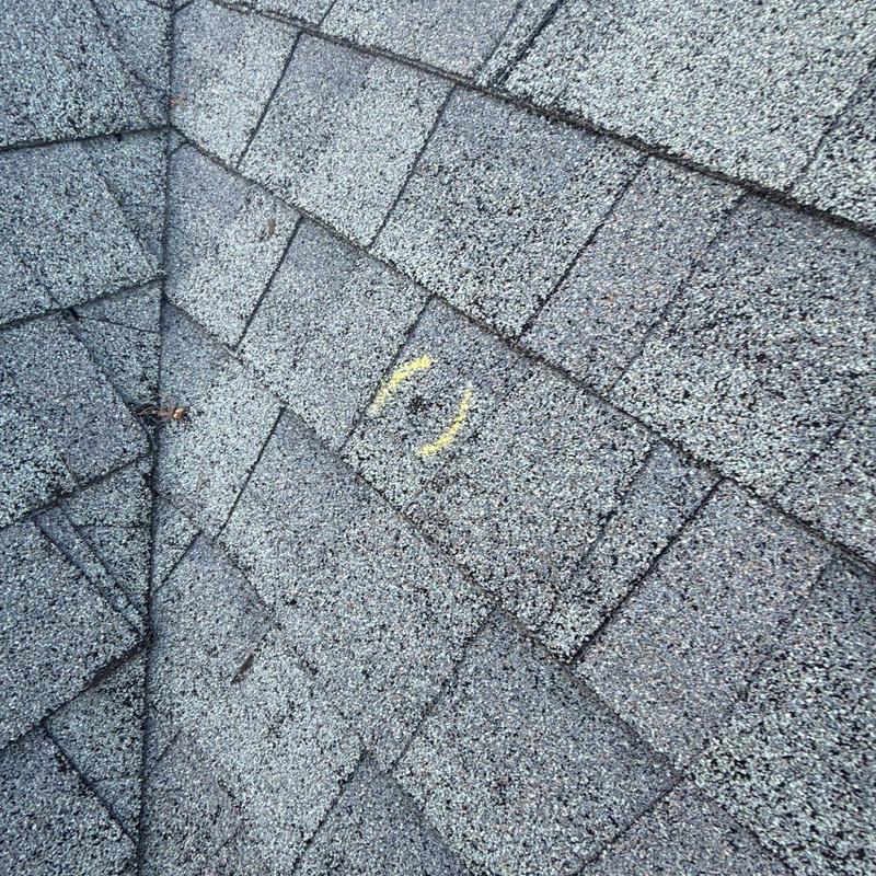 Roof shingles with yellow chalk marking indicating hail damage