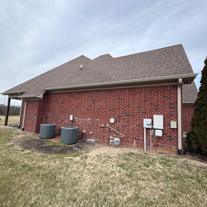Asphalt shingle roof with HVAC units and brick wall