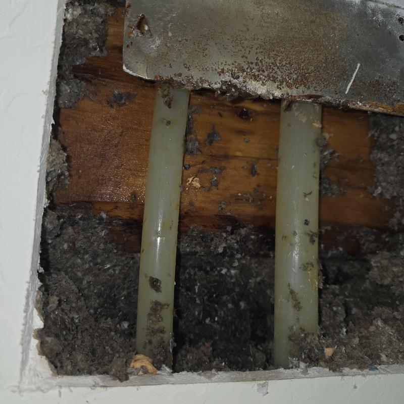 PEX water supply lines in attic with rusted metal bracket