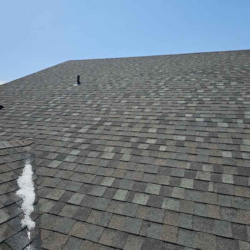 Asphalt shingle roof with visible hail damage and debris Asphalt shingle roof with visible hail damage and debris