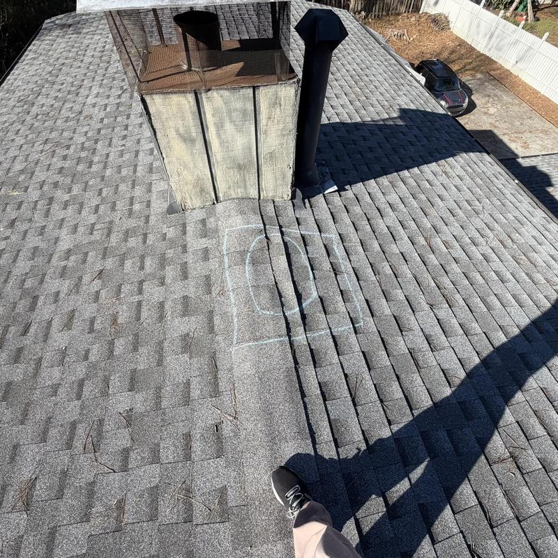 Roof shingles around chimney with marked repair area