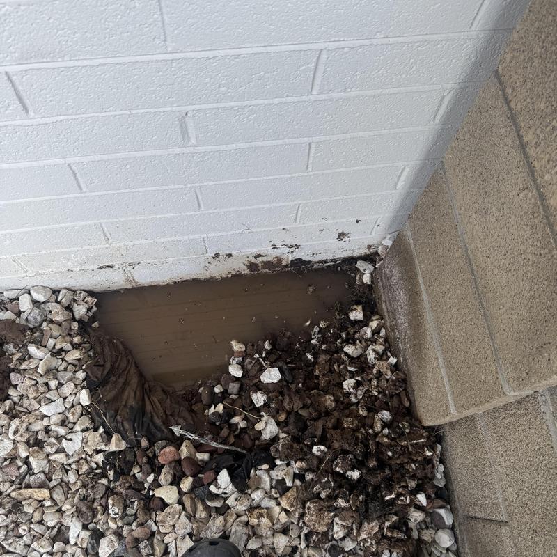 Water main leak excavation with muddy pooling near wall