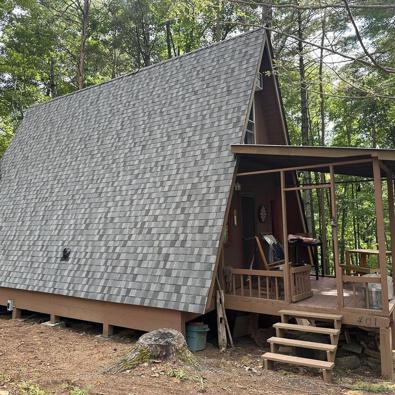 Shingle roof on A-frame cabin in wooded area