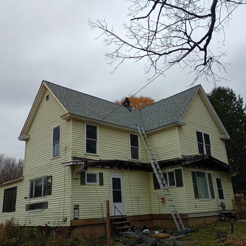 Shingle roof installation on two-story yellow house