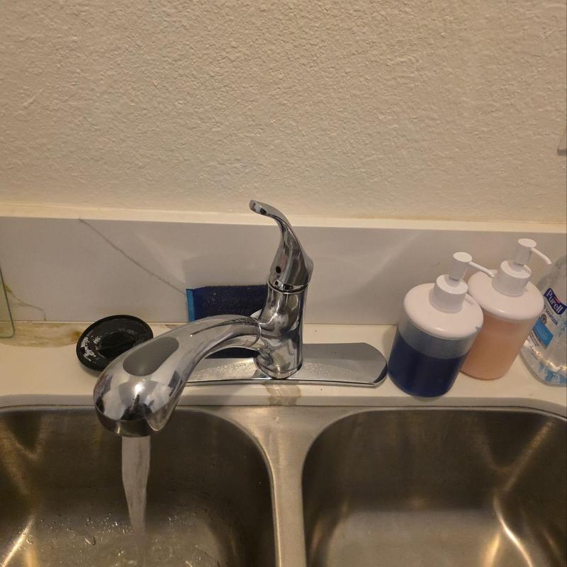 Kitchen faucet with water running above sink basin