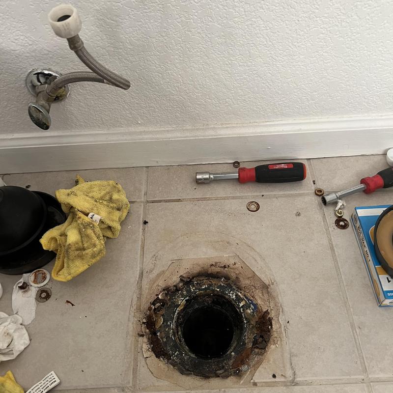 Toilet flange repair tools and parts on tile floor