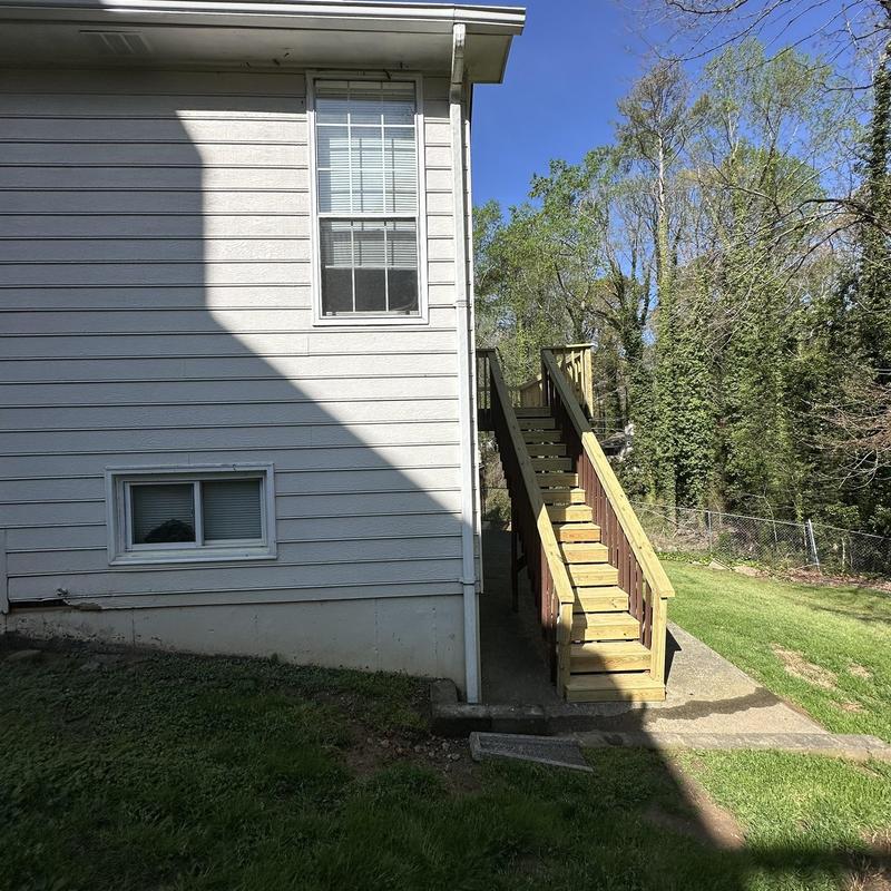 Downspout re-fastened on white house exterior wall