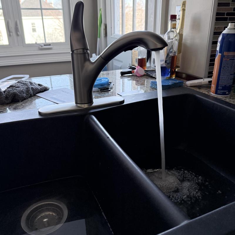 Kitchen faucet with water running over black sink Kitchen faucet with water running over black sink