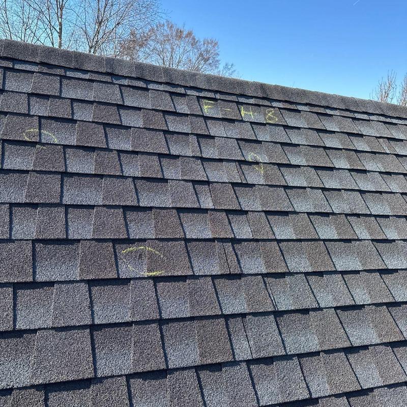 Asphalt shingles with hail damage marked for inspection