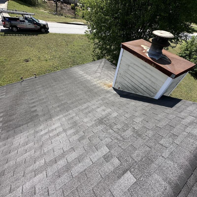 Asphalt shingle roof with rusted chimney cap and stains