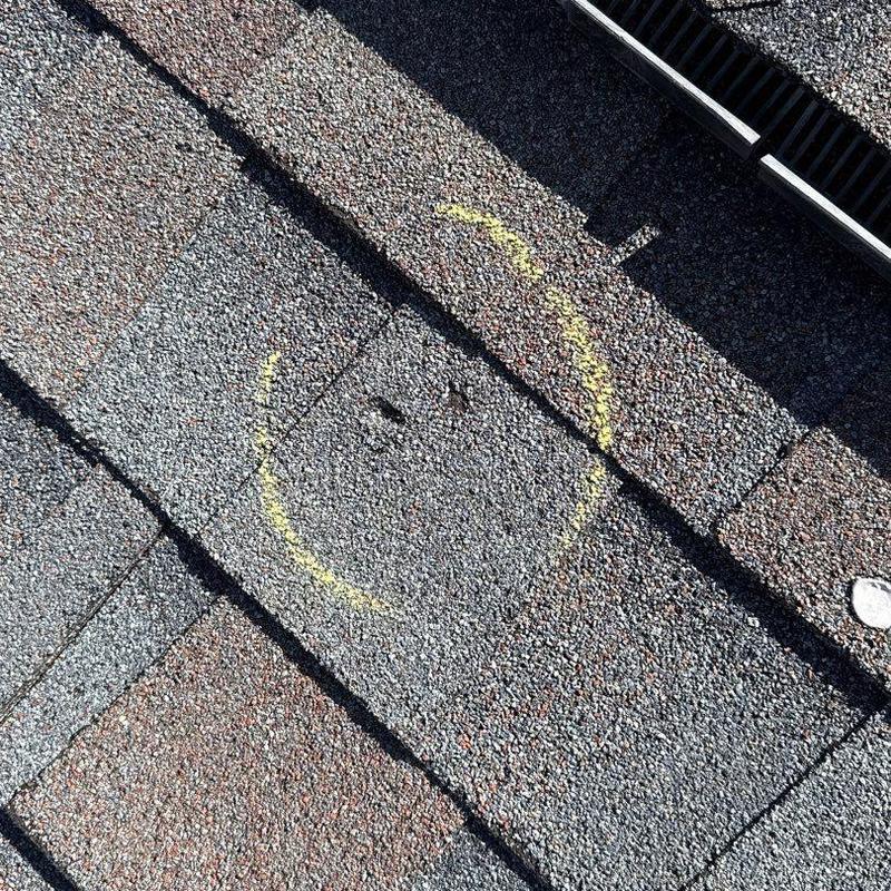 Shingle with yellow circle marking hail damage