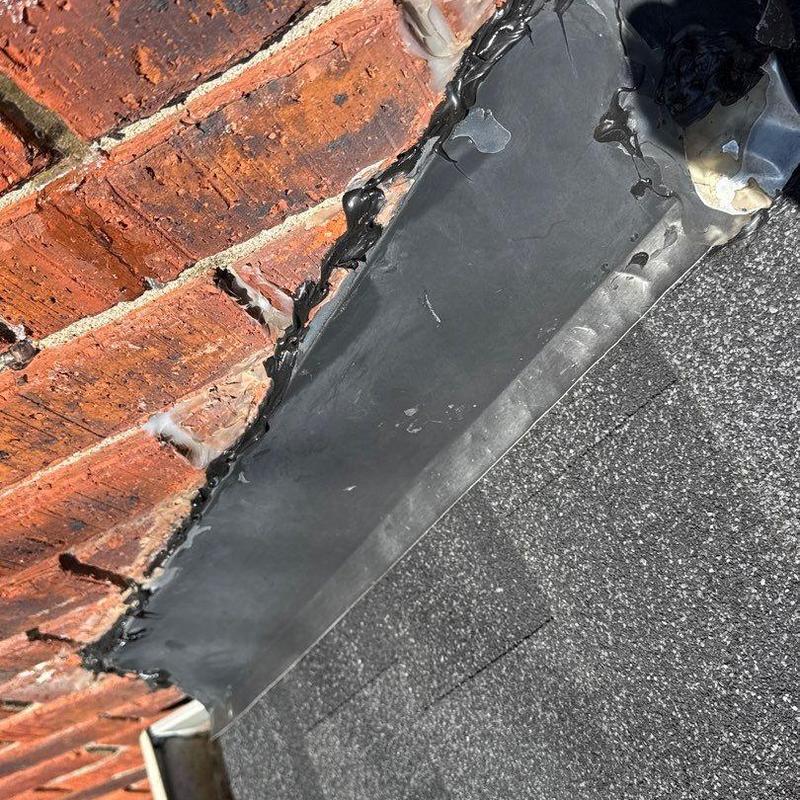 Roof flashing with sealant on brick wall and shingles