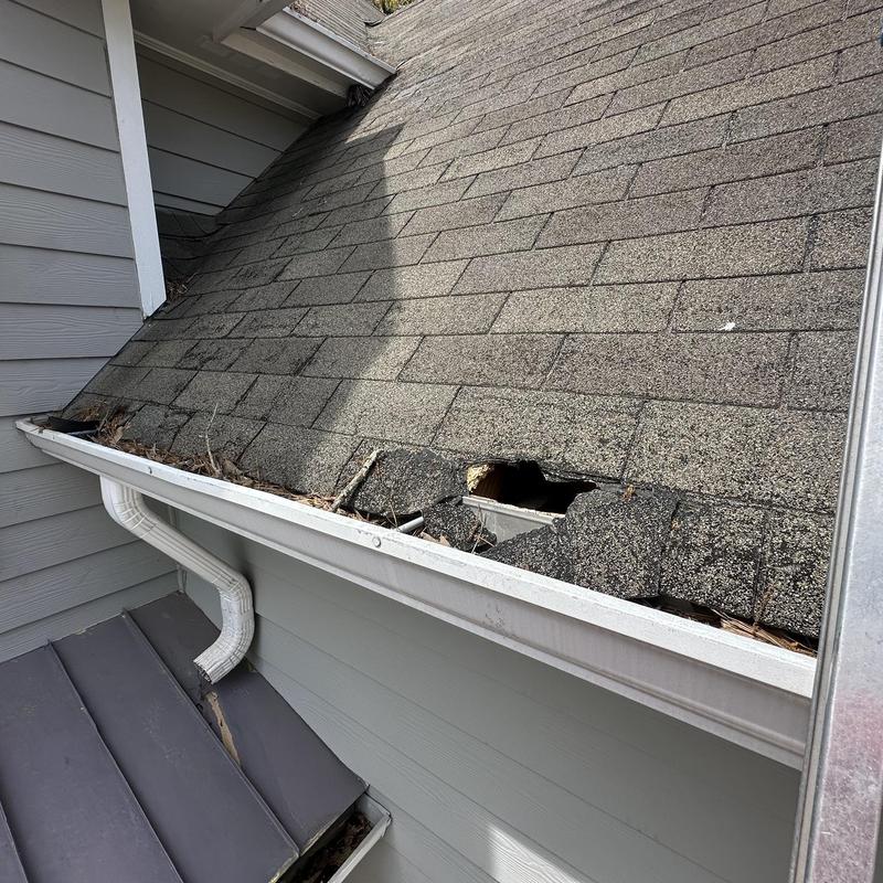 Garage roof shingles with large hole and damage
