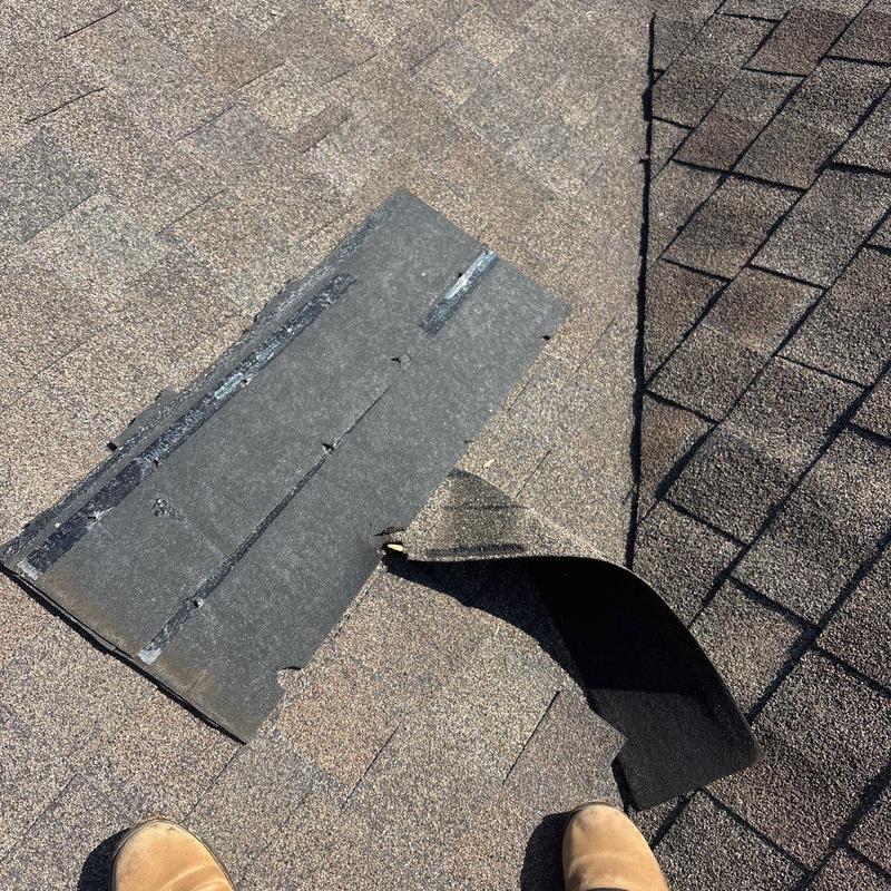 Roof shingles lifted showing damaged underlayment