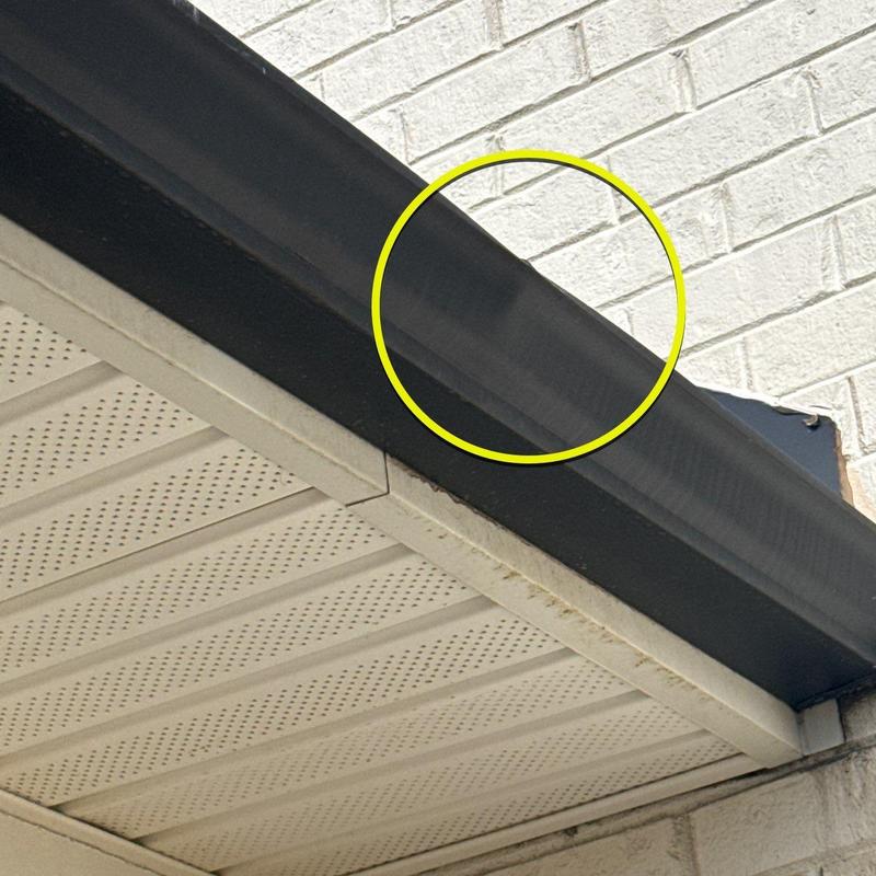 Roof edge flashing with dent damage marked in yellow circle