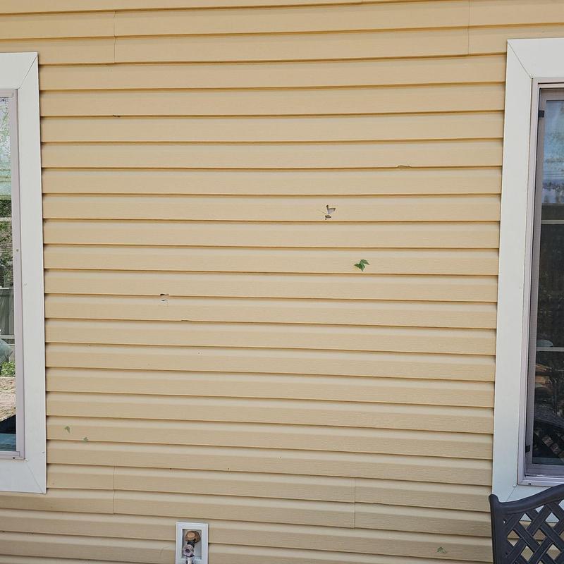 Vinyl siding with small hail impact dents and scratches Vinyl siding with small hail impact dents and scratches