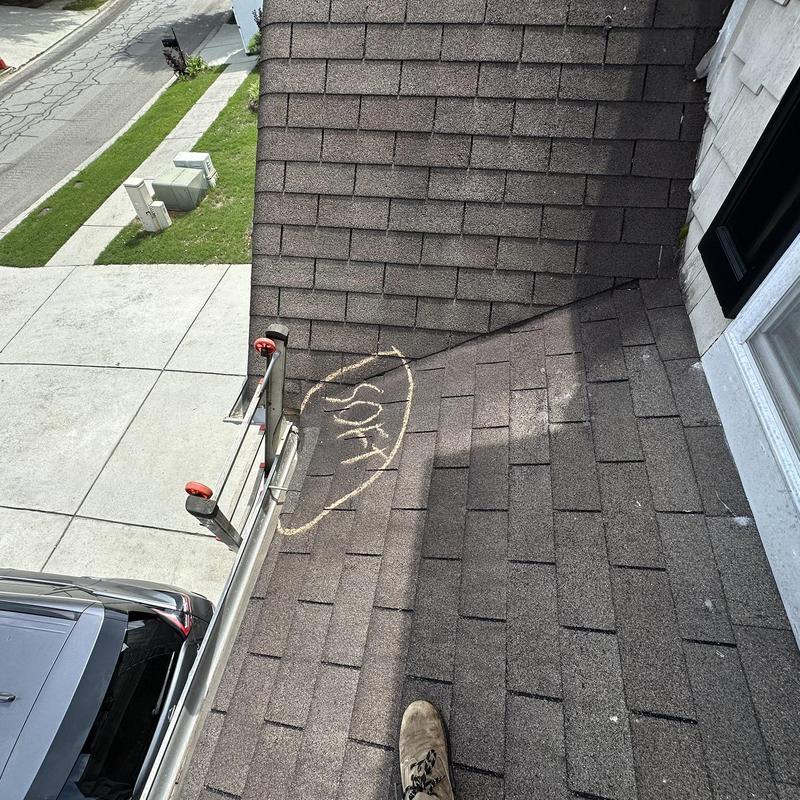 Roof shingles with chalk-marked damaged area on valley